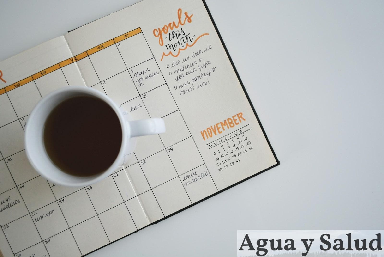 white ceramic mug with coffee on top of a planner